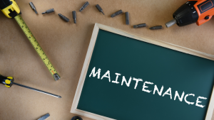 Chalkboard displaying the word “Maintenance” surrounded by tools such as a drill, screwdriver, tape measure, and drill bits, representing preventative maintenance planning for Toledo rental properties.